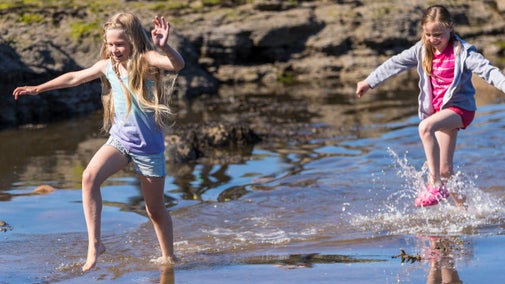 Girls paddling in a stream on the beach at Robin Hood's Bay, North Yorkshire